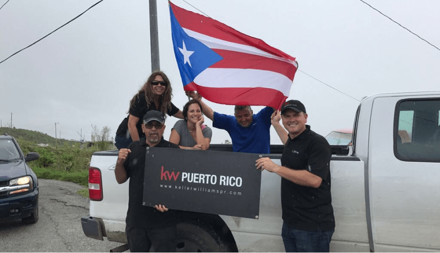 Photo of agents standing in front of a truck that is flying a Puerto Rico flag and holding a sign that says 